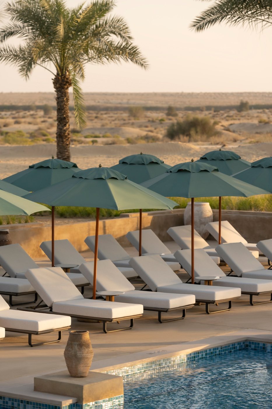 Poolside loungers with green umbrellas overlooking the desert